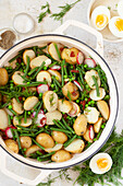Kartoffelsalat mit grünen Bohnen, Erbsen, gekochten Eiern, Rettich und sonnengetrockneten Tomaten