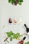 Red, rose and white wine in glasses, Branch of grape vine, bottles of wine on white background