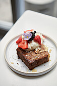 A slice of nut cake with cream and berries