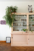 Pink display cabinet with collector's items and plant