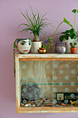 Vintage cupboard with glass doors, houseplants and decorative objects