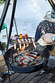 Grillen im Winter: Person brät Würstchen am Schwenkgrill