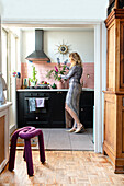 Woman decorates black kitchen unit with fresh flowers in vase