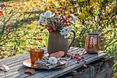 Herbstlicher Gartentisch mit Blumenstrauß aus Zierapfel und Chrysanthemen (Chrysanthemum)