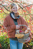 Woman with picnic basket under ornamental apple tree in autumn garden
