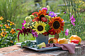 Blumenstrauß aus Sonnenblume 'Samtkönigin' (Helianthus), Sonnenhut 'Delicous Nougat' (Echinacea), Cosmea (Cosmos), Rosen 'Double Delight' (Rosa), Fuchsschwanz (Amaranthus), Zinnien (Zinnia), Storchschnabel, Kapuzinerkresse, Brokkoli, Paprika auf Gartenmauer