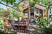 Bewachsene Veranda mit Sitzgruppe vor Gartenhütte