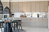 Modern kitchen with light-coloured fronts, dining table and pendant lights