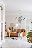 Wohnzimmer mit braunem Sofa, Kronleuchter und Weihnachtsbaum