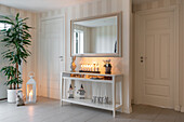 Hallway with console table, mirror and decorative lighting next to houseplant