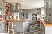 Modern kitchen with kitchen island, brick wall and grey and white checkered floor