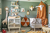 Crib with canopy, varied decoration and green walls in children's room