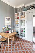 Kitchen with grey walls, terracotta tiles and cupboards