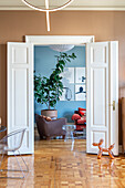 View through open double door to living room with parquet flooring, seating and houseplant