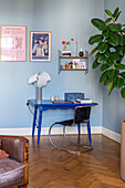 Work corner with blue desk and decorative shelf on blue wall