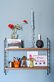 Shelf with decorations, candles and books on blue wall