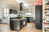 Modern kitchen with cooking island and black cabinets, bookshelf