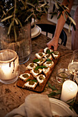 Canapés with pesto on a wooden board by candlelight