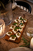 Canapés with cream cheese and pesto served on a wooden board