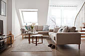 Helles Wohnzimmer mit neutralem Farbschema, beigem Sofa und Dachfenster