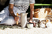 Picnic in the countryside with thermos flask and bouquet of flowers