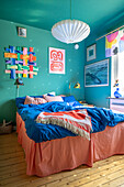 Bunter Wandbehang über Doppelbett im Schlafzimmer mit blauen Wänden