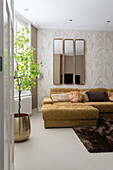 Corner sofa with cushions, wall mirror and houseplant in the living room