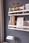 Wall shelf with decorative objects in front of patterned wallpaper