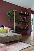 Living room with plant, wall shelves and coarse woven rug, wall colour in wine red