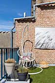 Hanging basket on balcony with artificial grass and ornamental grasses in pots