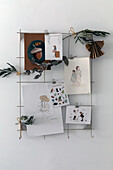 Decorative wall grid with sketches, cards and dried plants