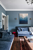 Living room with blue wall colour, velvet sofa and wooden floor