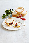 Mince pie on white plate with holly and berries christmas