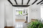 View of country-style kitchen with white cupboards, dark ceiling beams