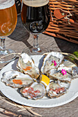 Freshly opened oysters with shallots, lemon, and sauce, served with beer