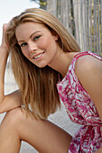 Blonde woman in pink and white summer dress on the beach