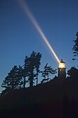 Heceta Head Lighthouse Shining Through The Oncoming Darkness; Oregon, United States Of America