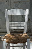 Ein traditioneller Taverna-Stuhl mit bemaltem Holz und Binsen-Sitz; Mykonos-Stadt, Mykonos, Kykladen, Griechische Inseln, Griechenland
