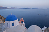 A Blue Domed Church And Pink Bell Tower Overlooking The Caldera At Dusk; Oia, Santorini, Cyclades, Greek Islands, Greece