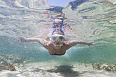 Ein junges Mädchen schwimmt unter Wasser an der Wasseroberfläche; Tarifa, Cadiz, Andalusien, Spanien