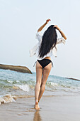 Junge Frau, die in einem Bikini am Strand spazieren geht; Xiamen, China