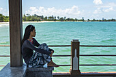 Eine junge Frau sitzt auf dem Pier am Independence Beach; Sihanoukville, Kambodscha
