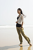 Junge Frau, die am Strand von Huohu, nördlich der Insel Kinmen, spazieren geht; Huohu, Taiwan
