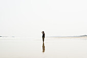 Junge Frau, die am Strand von Huohu, im Norden der Insel Kinmen, spazieren geht; Taiwan