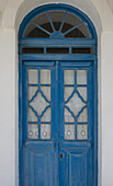 Eine traditionelle blau gestrichene Holztür mit Spitzenvorhängen; Pano Petali, Sifnos, Kykladen, Griechische Inseln, Griechenland