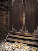 Japanese Shrine With Wooden Door And Slippers On Rock Steps; Kyoto, Japan