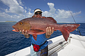 Fischer mit einem frisch gefangenen Roten Schnapper (Lutjanus); Tahiti