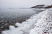 Pebbles In Calm Water With Ice And Snow Along The Shoreline Of Lake Superior