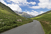 Eine gepflasterte Straße durch die Berge; Cumbria, England