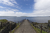 Person Standing At The End Of A Path At The Water's Edge Looking Out At The Water; Argyll And Bute, Scotland